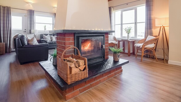 A living room with a fireplace, wooden floors, a sofa, and a dining area. - Eagle 3 Star - UKC5056 (Aviemore)