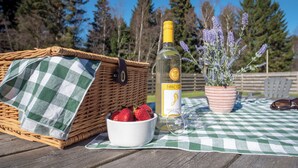 A picnic setup with a wicker basket, a bowl of strawberries, a bottle of wine, a glass, and a potted lavender plant on a checkered tablecloth. - Eagle 3 Star - UKC5056 (Aviemore)