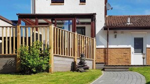 A residential property with a paved driveway, a wooden fence, and a stone stack. - Ruby Cottage-UKC5064 (Aviemore)