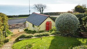 A small house with a red door, a garden with a hedge, and a view of the sea. - Bonito is situated in Ventnor with panoramic sea views. (Ventnor)