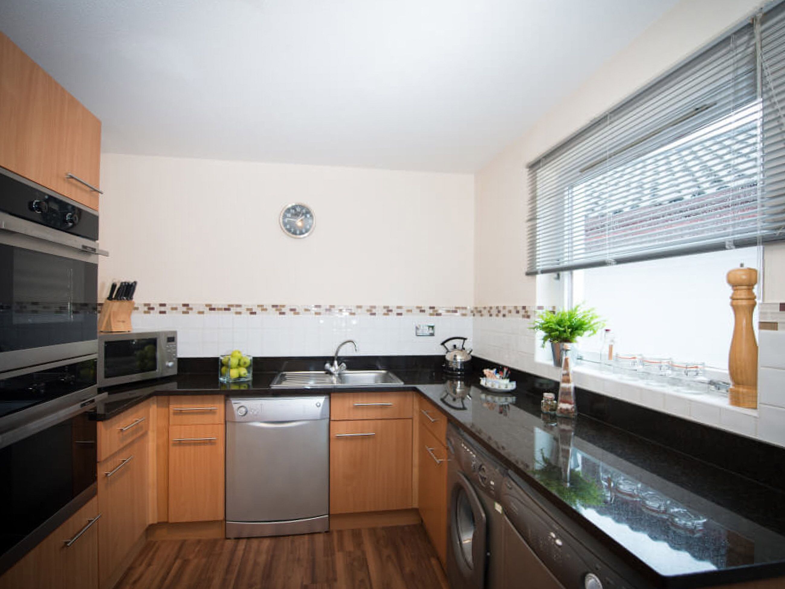 A modern kitchen with wooden cabinets, a dishwasher, a microwave, and a sink.