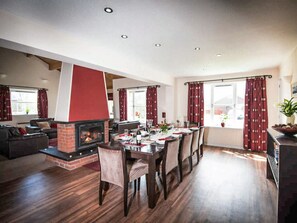 A spacious living area with a fireplace, dining table set for four, and a cozy seating arrangement. - 4 bedroom accommodation in Aviemore (Aviemore)