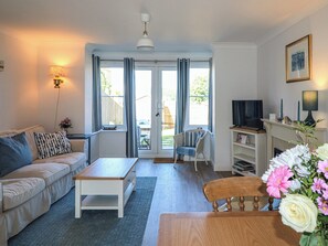 Ein Wohnzimmer mit Sofa, Couchtisch, Fernseher und einem Esstisch mit Stühlen.