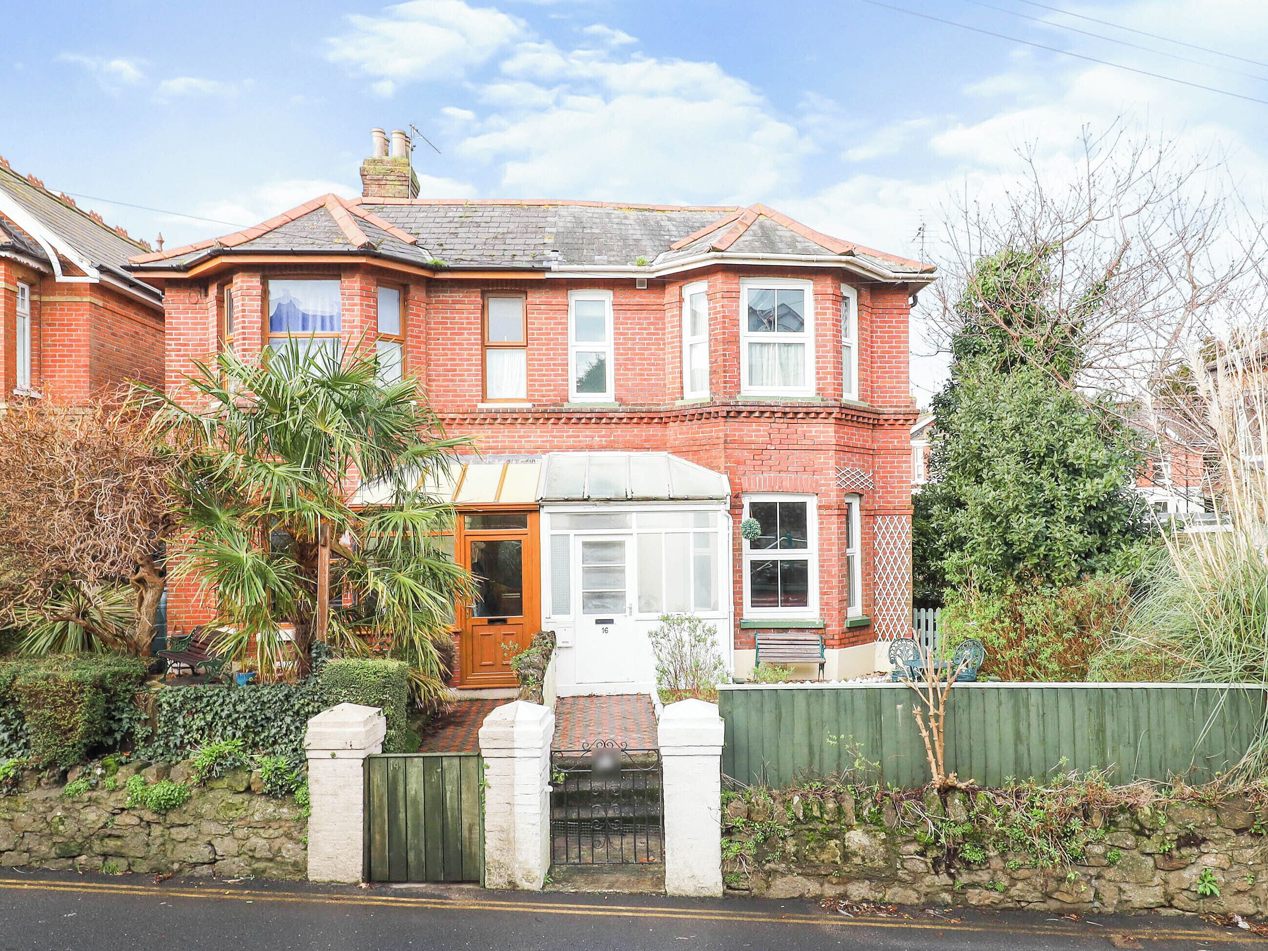 A red brick house with a bay window, a front door, and a small porch.