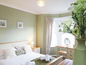 A hotel room with a bed, bedside table, lamp, and a window with curtains. - 3 bedroom accommodation in Shanklin (Shanklin)