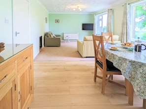 A spacious room with a wooden dining table, a sofa, and a television. - Hilltops is ideally situated to explore all the Island of Wight has to offer. (Wroxall, near Ventnor)