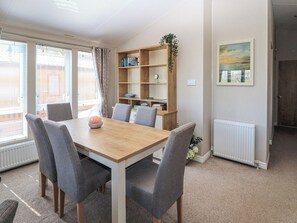 A dining area with a wooden table and grey chairs, a bookshelf with books and decorative items, and a window with blinds. - No 7 North - UKC5129 (Ryde)