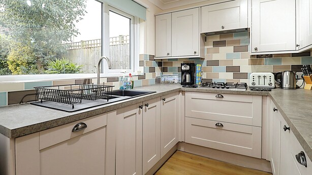 A modern kitchen with white cabinets, a granite countertop, and a window overlooking a garden. - 4 bedroom accommodation in Ryde (Ryde)