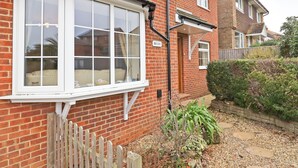 A red brick house with a white window and a wooden fence. - 4 bedroom accommodation in Ryde (Ryde)