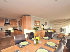 A modern kitchen with built-in appliances, a dining area with a table set for four, and a living area with a sofa and TV. - 3 bedroom accommodation in Ventnor (Ventnor)