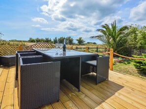 An outdoor patio with a glass-top table, wicker chairs, and a bottle of champagne. - 3 bedroom accommodation in Bembridge (Bembridge)