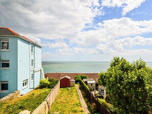 Ein Küstenanwesen mit Meerblick, ein hellblaues Gebäude und ein eingezäunter Gartenbereich.
