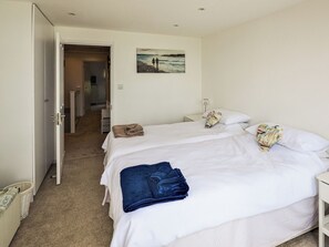 Ett hotellrum med två sängar, en tavla på väggen och en hall som leder till ett badrum.