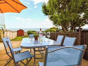 An outdoor patio with a table set for two, a bottle of wine, and two glasses. - 3 bedroom accommodation in Ventnor (Ventnor)