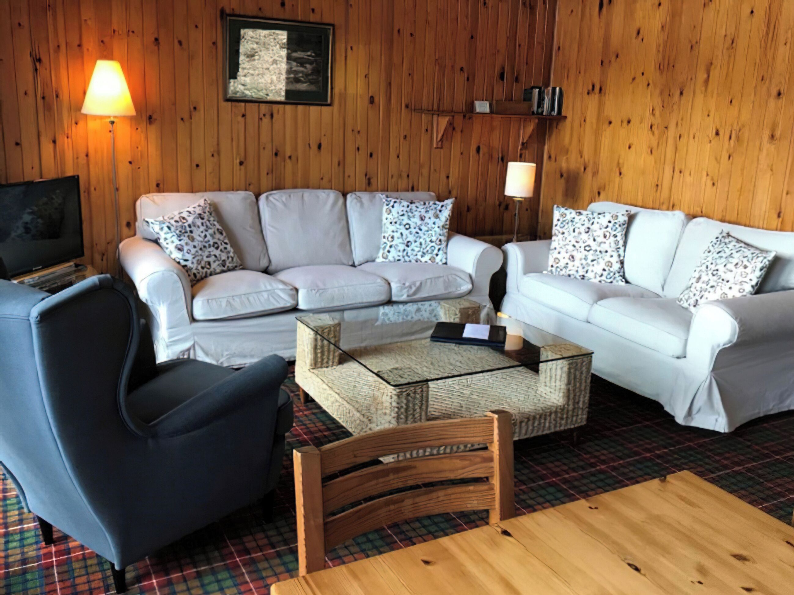 A cozy living room with a sectional sofa, a wooden coffee table, and a plaid rug.