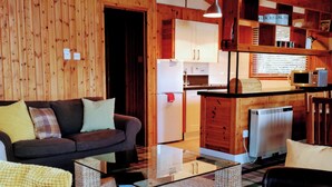 Una sala acogedora con un sofá, una mesa de centro de vidrio y un sillón de mimbre.