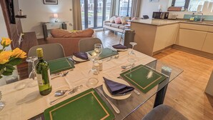 Un comedor con una mesa dispuesta para cuatro personas, con individuales verdes y cubiertos.