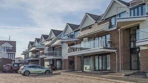 Una hilera de casas adosadas modernas con balcones, un camino de grava y un coche aparcado.