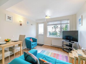 A living room with a sofa, a TV, a dining table with chairs, and a window with blinds. - 1 Mount Brioni - UKC5338 (Torpoint)