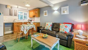 Ett kompakt bostadsutrymme med ett kök, en matplats och en sittgrupp med en lädersoffa och ett soffbord.
