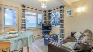 A dining area with a table set for two, a television, and a sofa. - 8 Mount Brioni - UKC5343 (Torpoint)