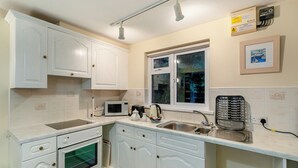 A compact kitchen with white cabinetry, a built-in oven, a microwave, a kettle, and a sink. - 8 Mount Brioni - UKC5343 (Torpoint)