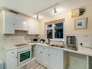 A compact kitchen with white cabinetry, a built-in oven, a microwave, a kettle, and a sink. - 8 Mount Brioni - UKC5343 (Torpoint)