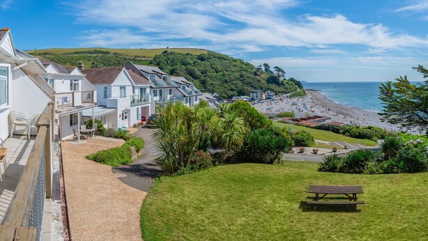 Une zone résidentielle côtière avec des maisons, une plage et une colline herbeuse.