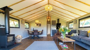A spacious loft with a high ceiling, a central dining area, a sofa, a coffee table, and a fireplace. - 2 bedroom accommodation in Stanton-On-The-Wolds (Stanton-On-The-Wolds)