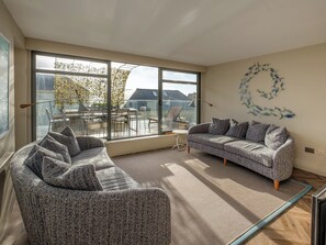A modern living room with a large window, a sofa, a chair, and a decorative fish wall art. - 3 bedroom accommodation in Ventnor (Ventnor)