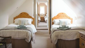 Une chambre à coucher avec deux lits, chacun doté d’une tête de lit en bois, d’une chaise et d’une commode.