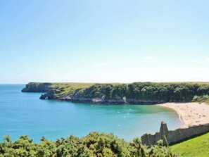 Un paysage côtier avec une plage, des falaises et un ciel dégagé.