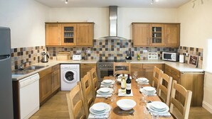 Une cuisine moderne avec des meubles en bois, un lave-linge encastré et un coin repas aménagé pour prendre un repas.
