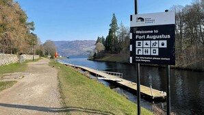 Ein Schild, das Besucher in Fort Augustus willkommen heißt und Annehmlichkeiten wie ein Boot, einen Picknickbereich und eine Toilette zeigt.