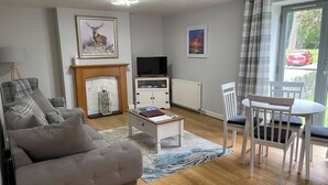 Ein Wohnzimmer mit Sofa, Couchtisch, Kamin, Fernseher und einem Essbereich mit Tisch und Stühlen.