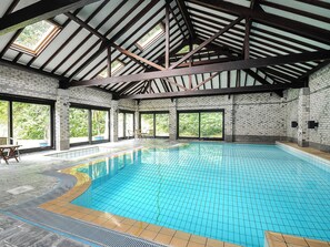 A large indoor swimming pool with a tiled floor and a high ceiling with exposed beams. - Number Three - UKC4965 (Tawstock, near Barnstaple)