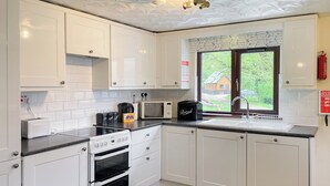 Una cocina moderna con armarios blancos, encimera negra, horno empotrado, microondas y ventana con vistas al exterior.