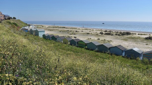 A coastal area with beach huts and a building on a hillside. - 2 bedroom accommodation in Pakefield (Pakefield)