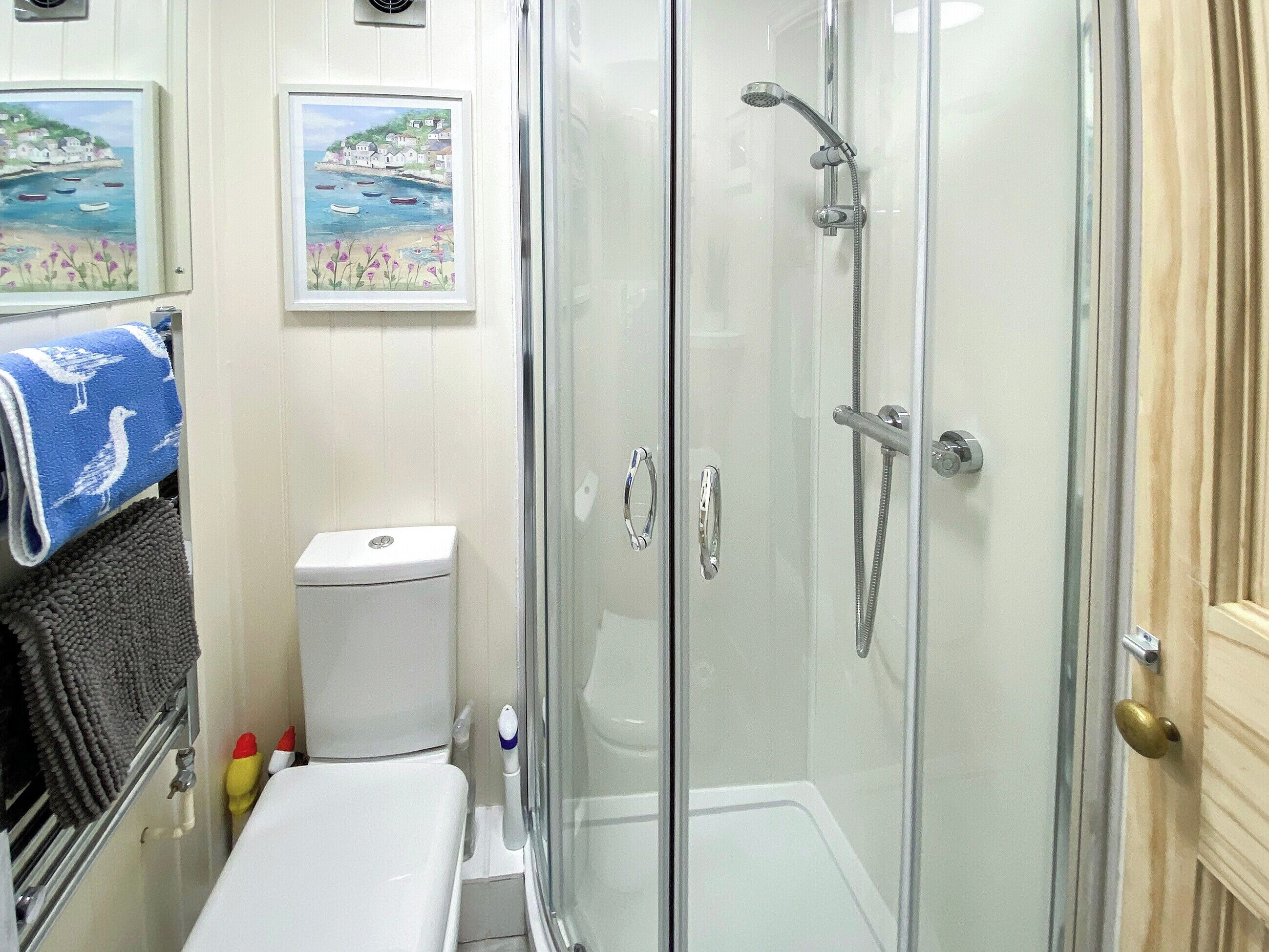 A bathroom with a glass-enclosed shower, a toilet, and a sink.