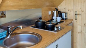 Eine kompakte Küche mit Spüle aus Edelstahl, Wasserkocher, Toaster und Kaffeemaschine auf einer Holzausziehtafel.
