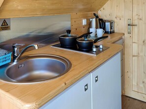 Een compacte keuken met een RVS spoelbak, een waterkoker, een broodrooster en een koffiezetapparaat op een houten aanrecht.