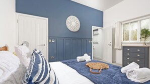 A bedroom with a bed, a dresser, a wall decor, and a window with blinds. - Little Dunley Cottages - Apple Lodge (Bovey Tracey)