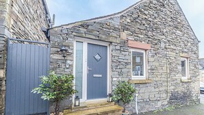 A stone house with a grey door, a small window, and a set of steps leading to the entrance. - 2 bedroom accommodation in Millom, near Haverigg (Millom, near Haverigg)