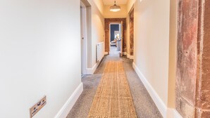 A hallway with a carpet, a radiator, and a ceiling light fixture. - 2 bedroom accommodation in Millom, near Haverigg (Millom, near Haverigg)