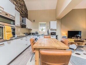 A modern kitchen with white cabinets, a wooden dining table, and leather chairs. - 2 bedroom accommodation in Millom, near Haverigg (Millom, near Haverigg)