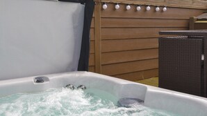 Ein Whirlpool mit Wasserdüsen, einer Steuerung und einem Holzzaun im Hintergrund.