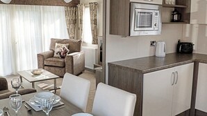 Ein kompaktes Hotelzimmer mit Essbereich, einer Couch, einer Küche mit Mikrowelle und einer kleinen Ablage mit Küchenutensilien.
