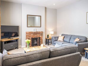 A living room with a TV, sofa, fireplace, and a clock on the wall.