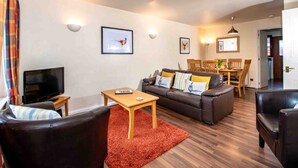 Ein Wohnzimmer mit einer Couch, einem Couchtisch, einem Fernseher und einem Essbereich mit Stühlen und Tisch.