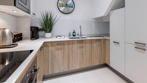 Een moderne keuken met een ingebouwde oven, een koffieapparaat, een spoelbak en een klok waarop 'LONDON' staat.